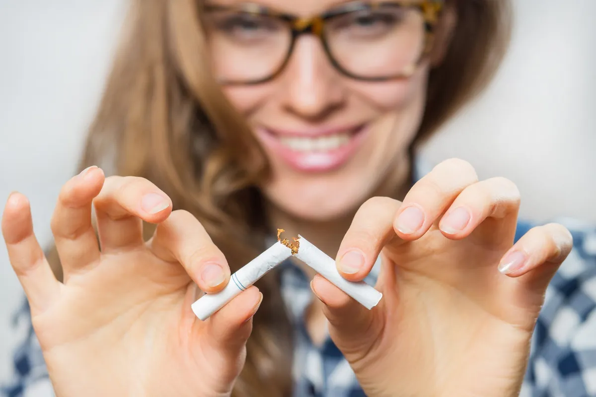 Femme souriante cassant une cigarette.