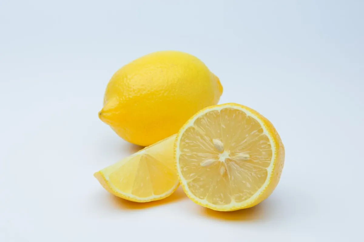 Citrons jaunes entiers et coupés, posés sur un plan de travail.