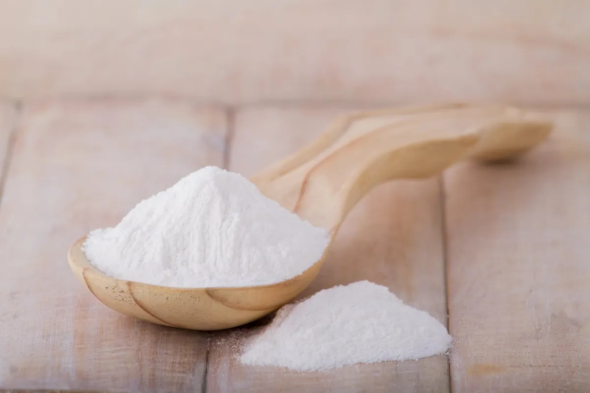 Cuillère en bois avec farine blanche.