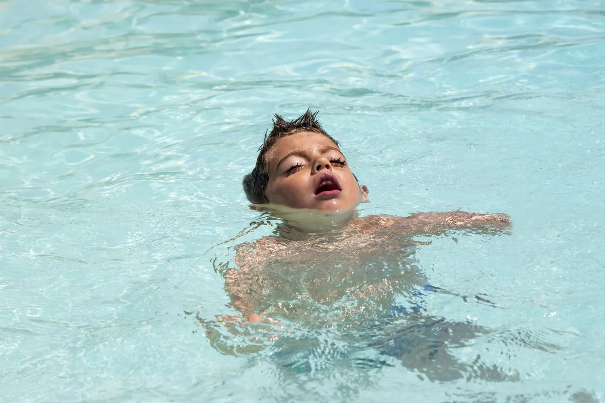Enfant nageant paisiblement dans une piscine.
